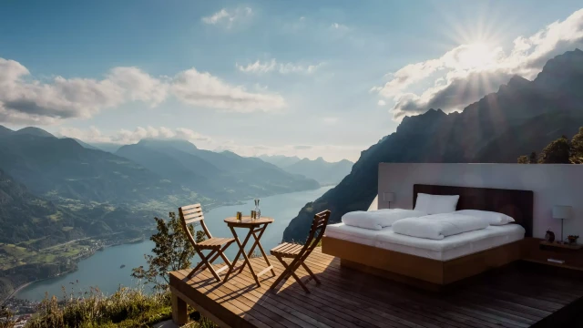 Ein Bett und Tisch und Stühle auf einer Holzplattform vor einer Bergkulisse