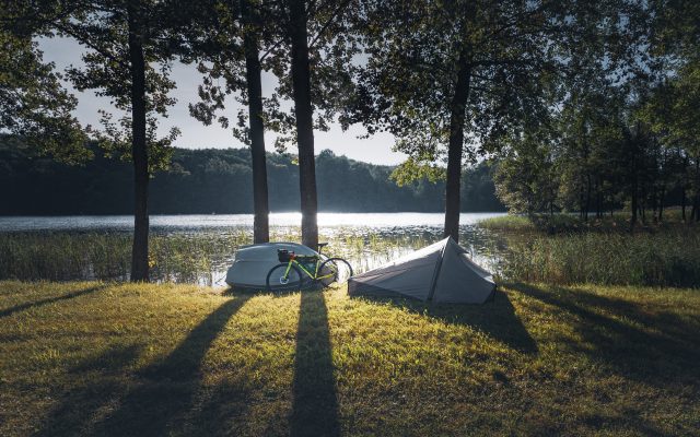 Ein Bikepacking Rad und ein Zelt vor einem See