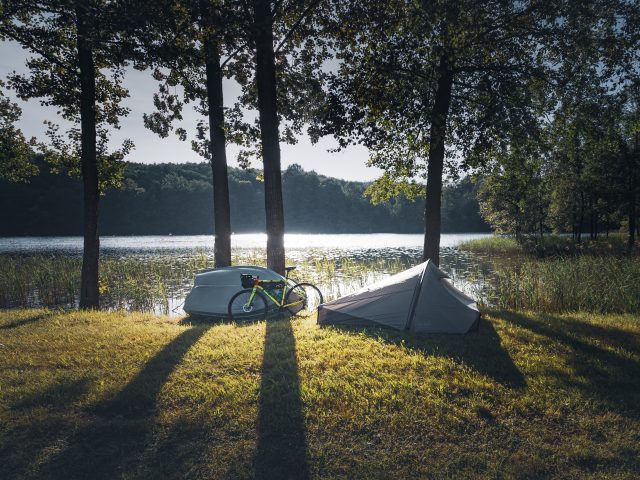 Ein Bikepacking Rad und ein Zelt vor einem See